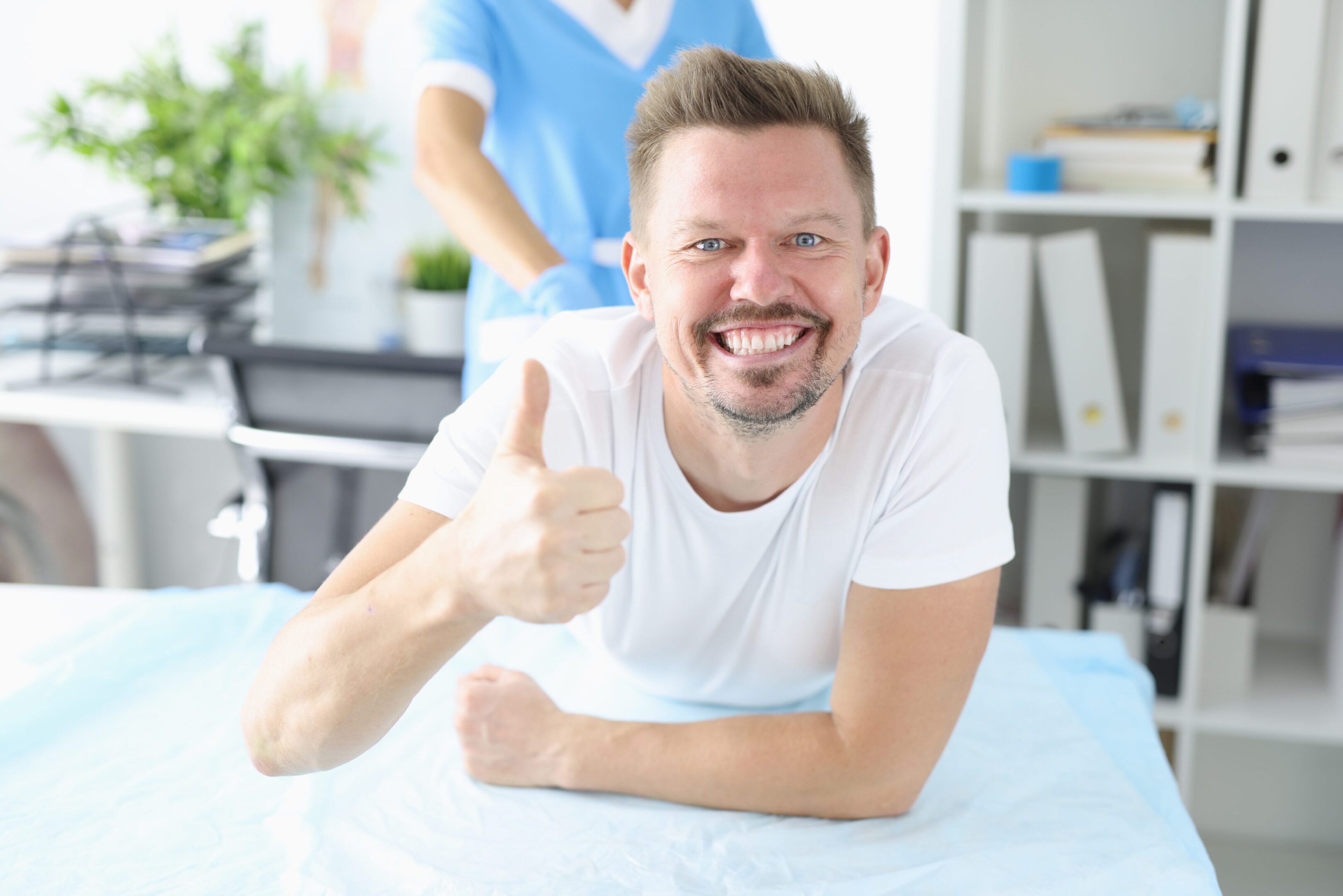 Man lying down, giving thumbs up.