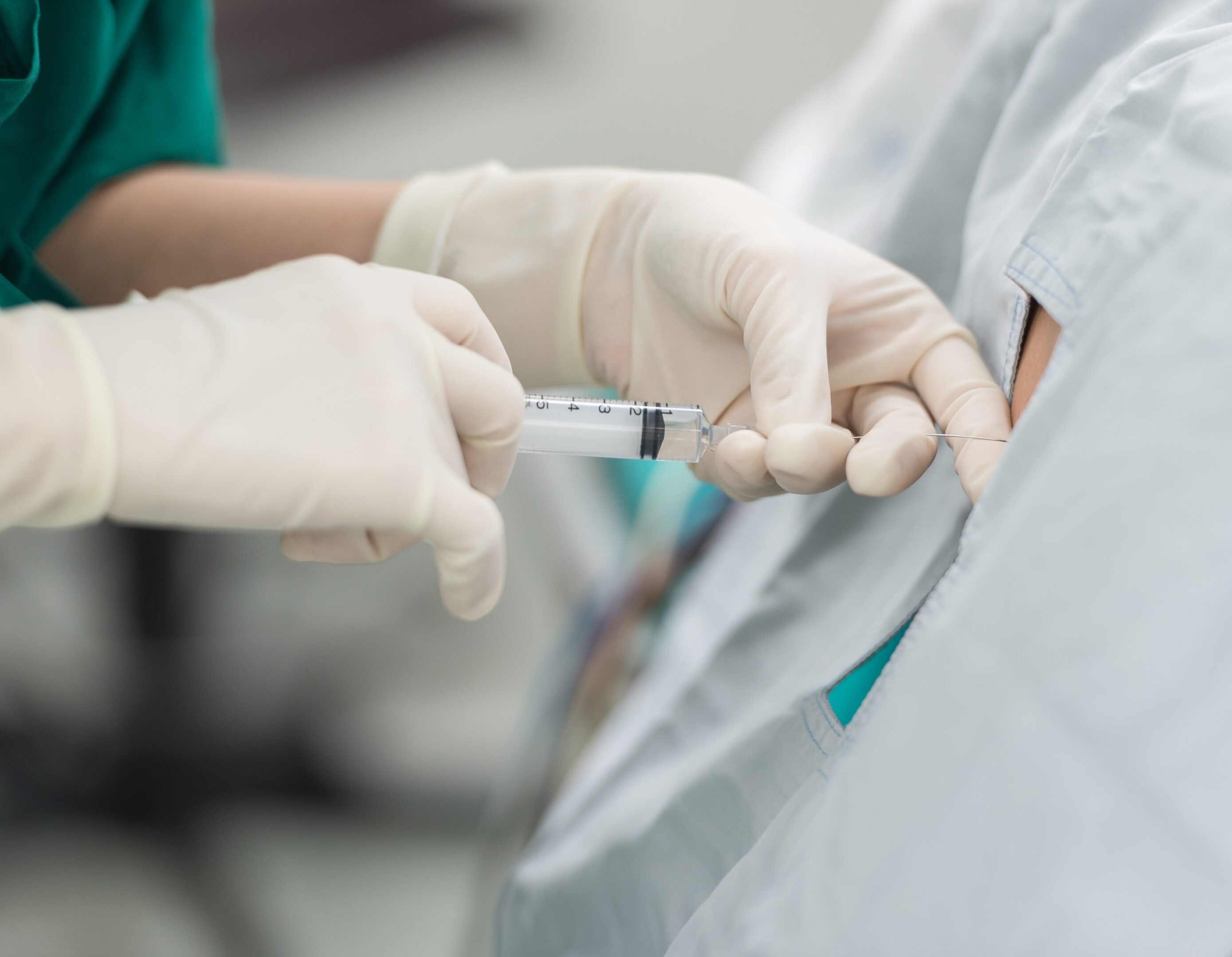 Injection administered by gloved hands in hospital.